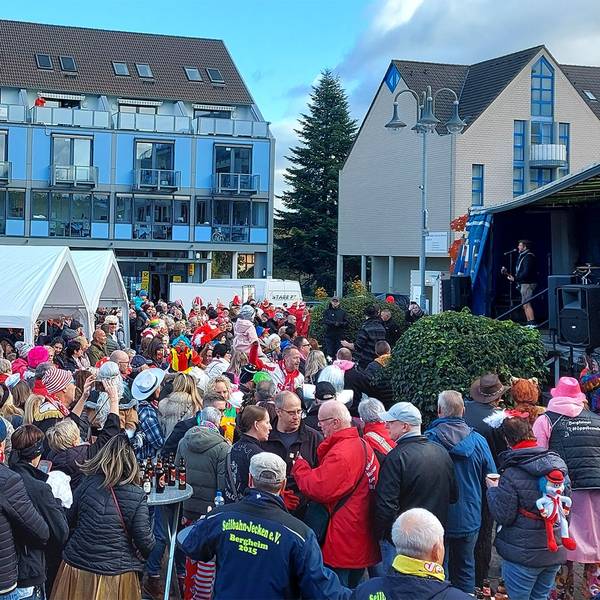 Viele bunt kostümierte Menschen stehen zum Karnevalsauftakt in Mechernich vor einer Bühne.