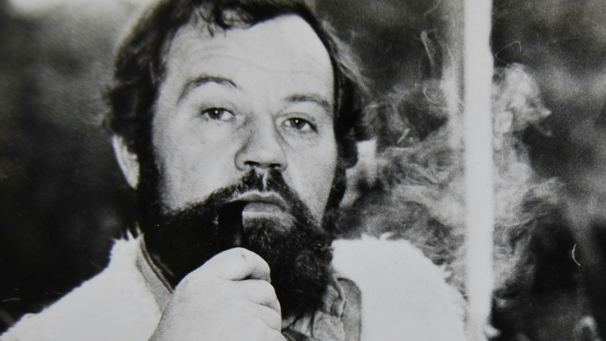 Ein bärtiger Mann raucht Pfeife.