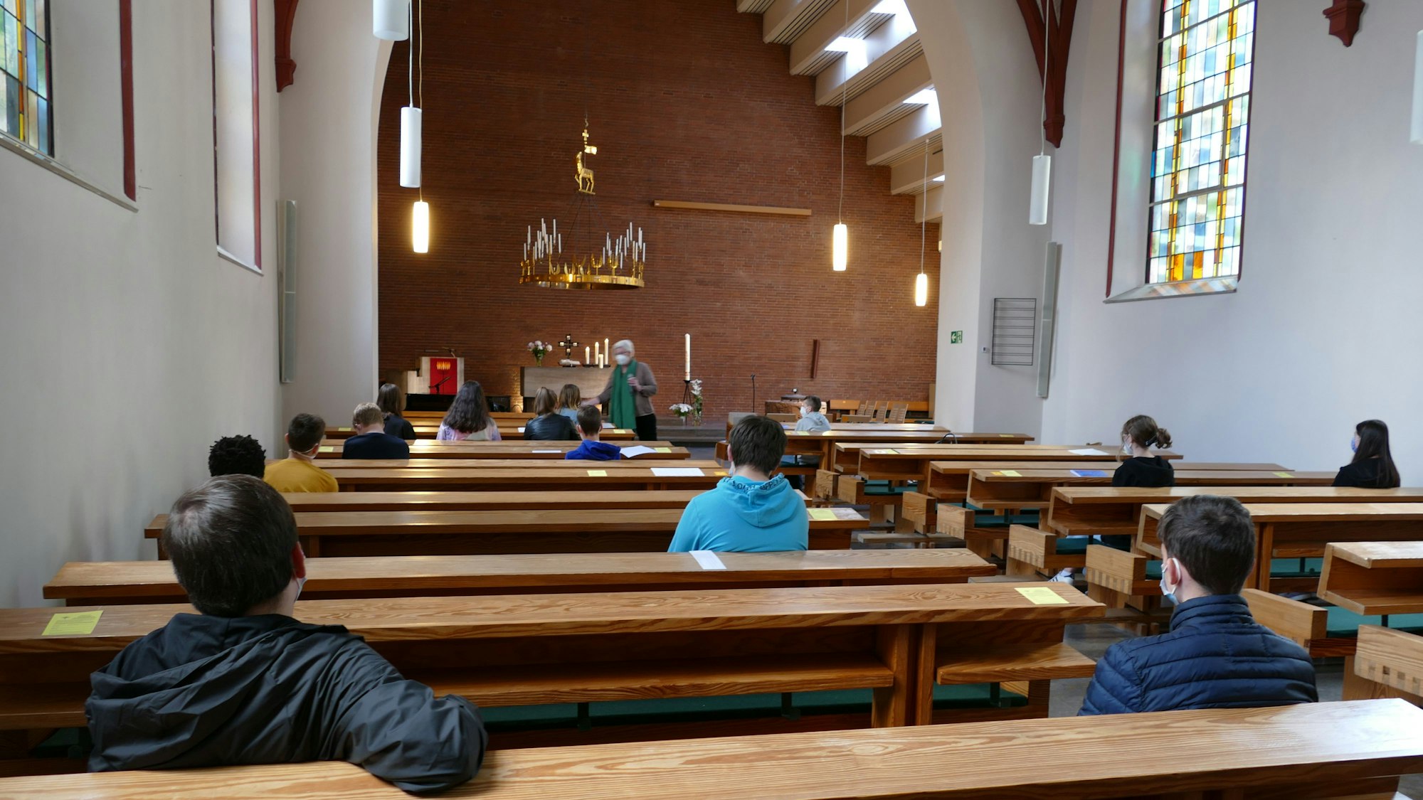 Kinder sitzen in einer Kirche. Sie tragen Corona-Masken.
