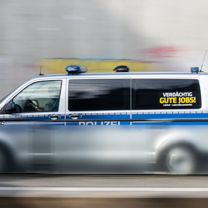 Ein Polizeiauto mit der Aufschrift ·Verdächtig gute Jobs!· fährt eine Straße entlang. (Aufnahme mit langer Belichtungszeit)
