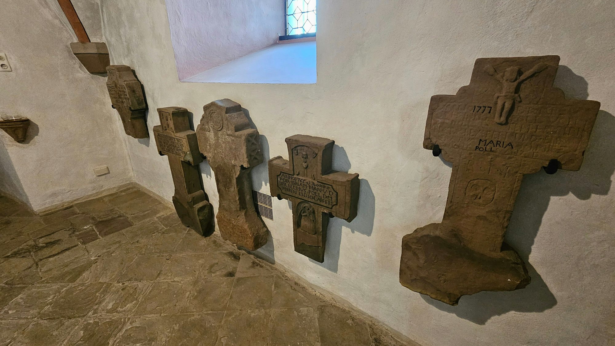 Alte Steinkreuze hängen an einer Wand des Turms.