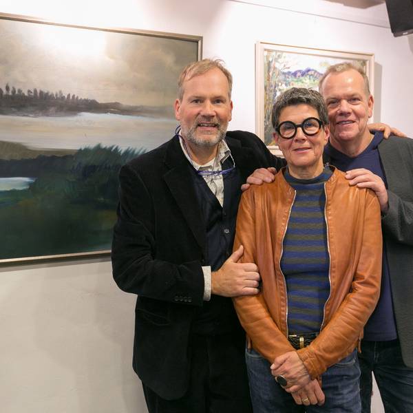 Zwei Herren und eine Dame stehen vor Bildern in einem Ausstellungsraum.