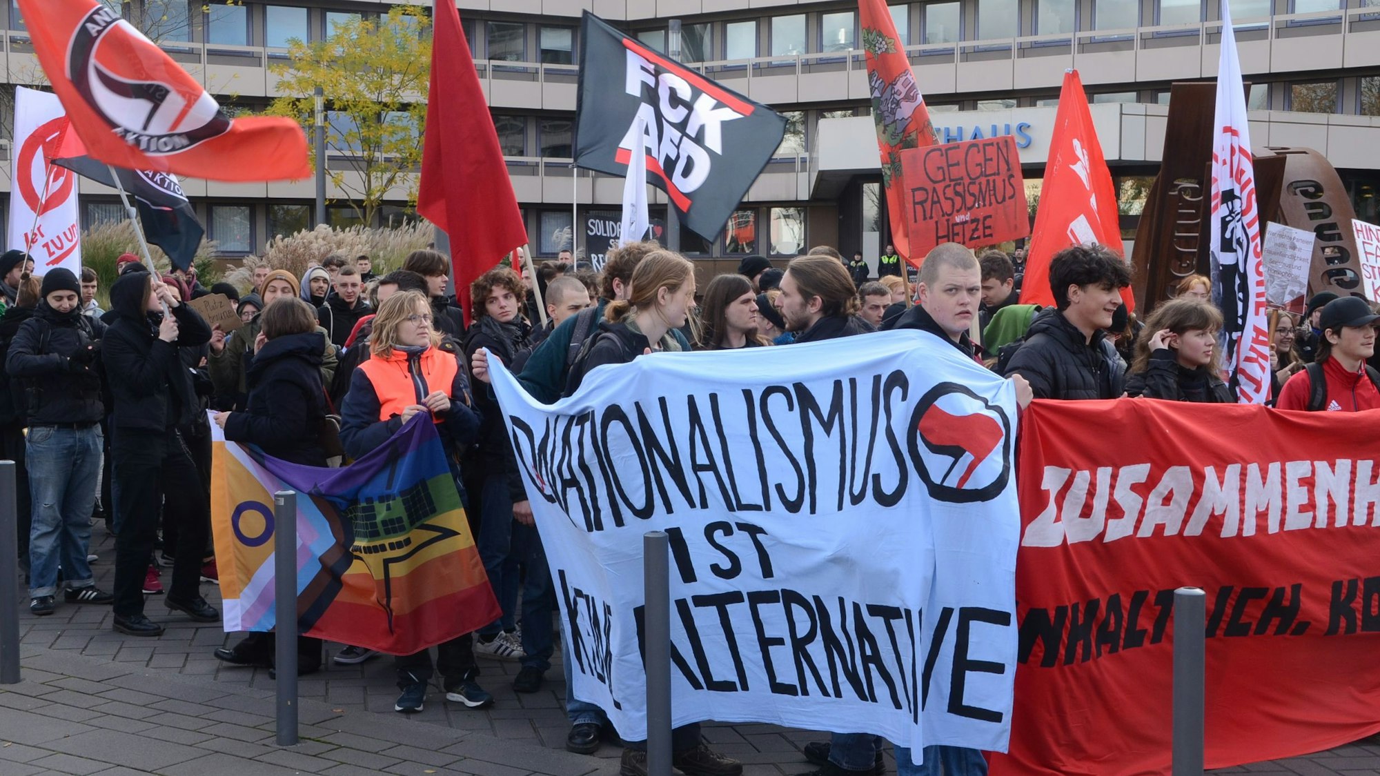 Demonstranten vor der Stadthalle, im Hintergrund ist das Troisdorfer Rathaus zu sehen. Die Demonstranten tragen Transparente mit Aufschriften wie „Nationalismus ist keine Alternative“.