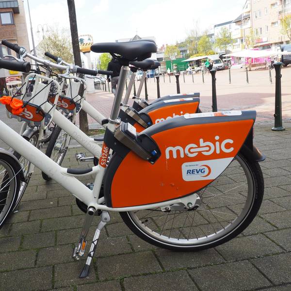 Zu sehen sind weiße Mietfahrräder mit dem orangefarbenen Schriftzug Mobic.