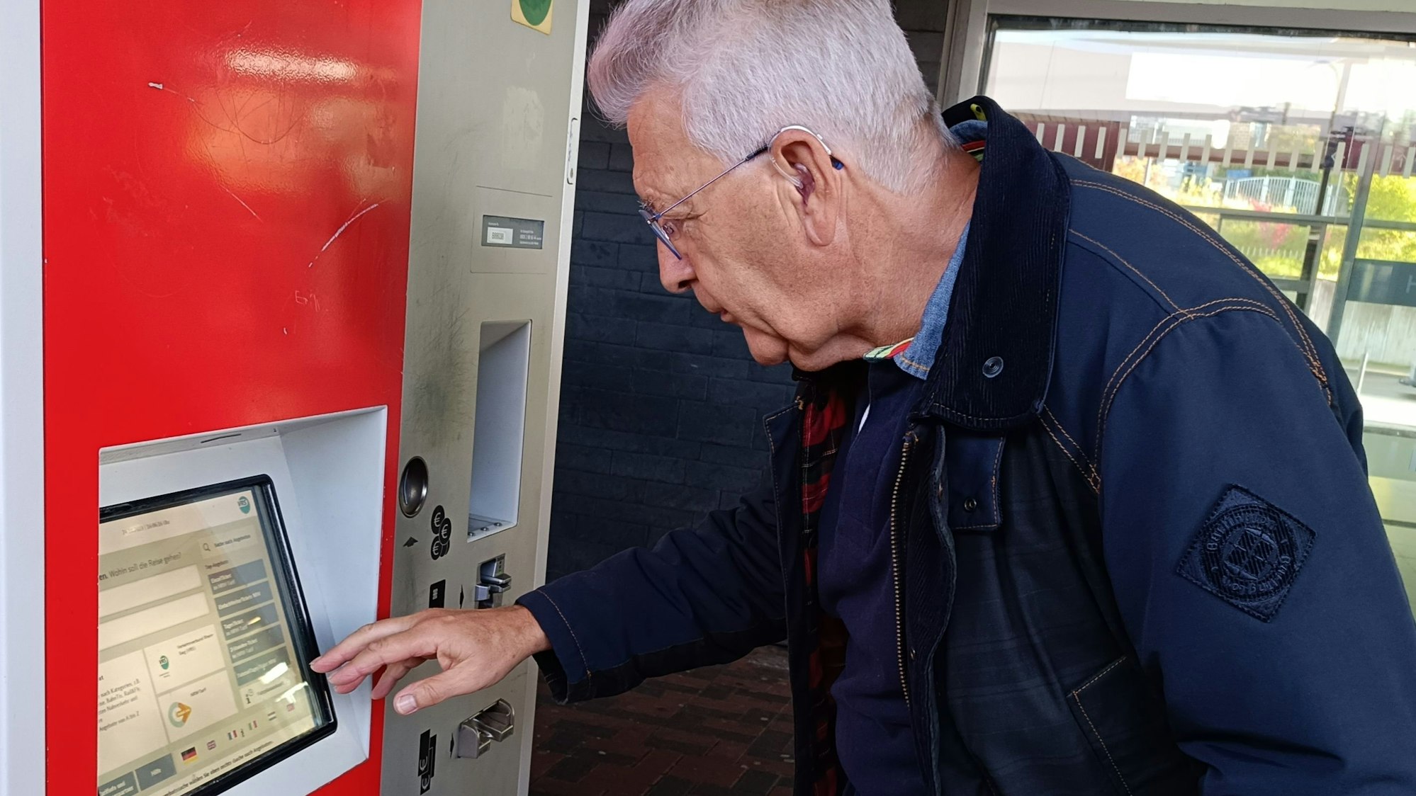 Ein Mann steht an einem Ticketautomaten.