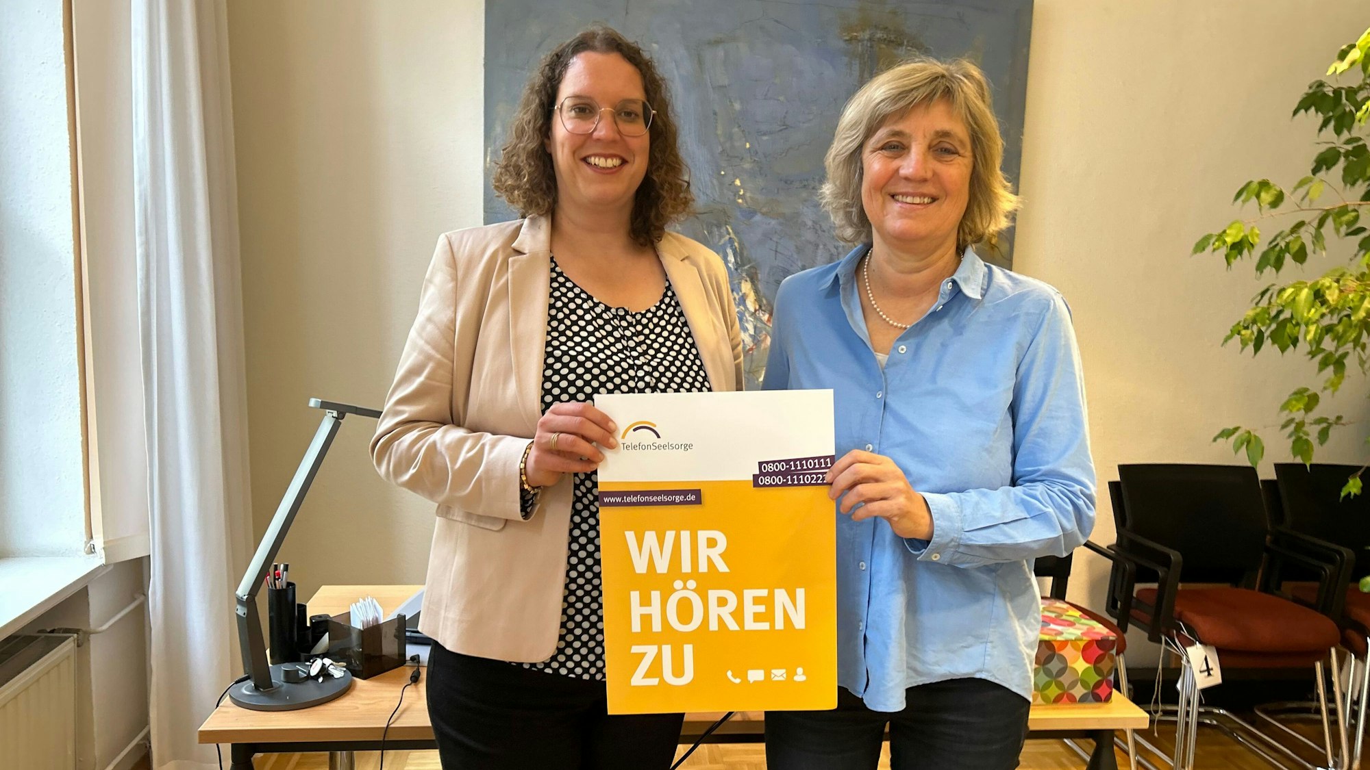 Dorit Felsch und Annelie Bracke halten ein Schild auf dem „Wir hören zu“ steht.