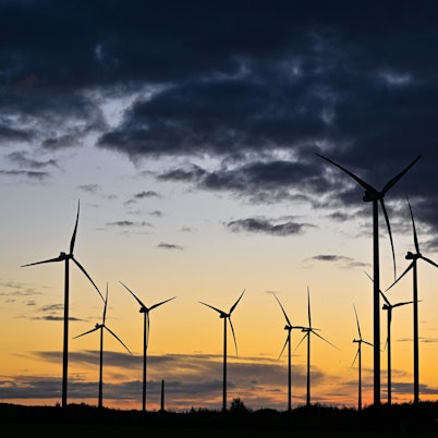 Der Sonnenaufgang leuchtet über einem Windenergiepark.