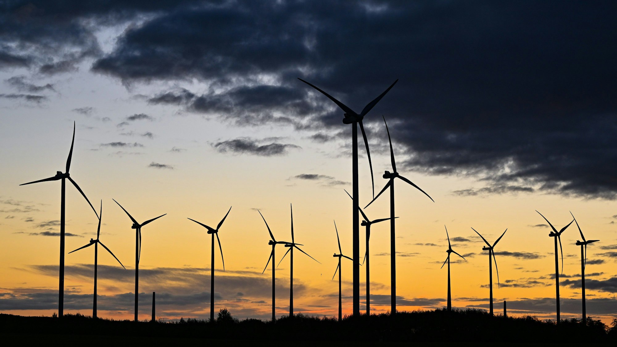 Der Sonnenaufgang leuchtet über einem Windenergiepark.