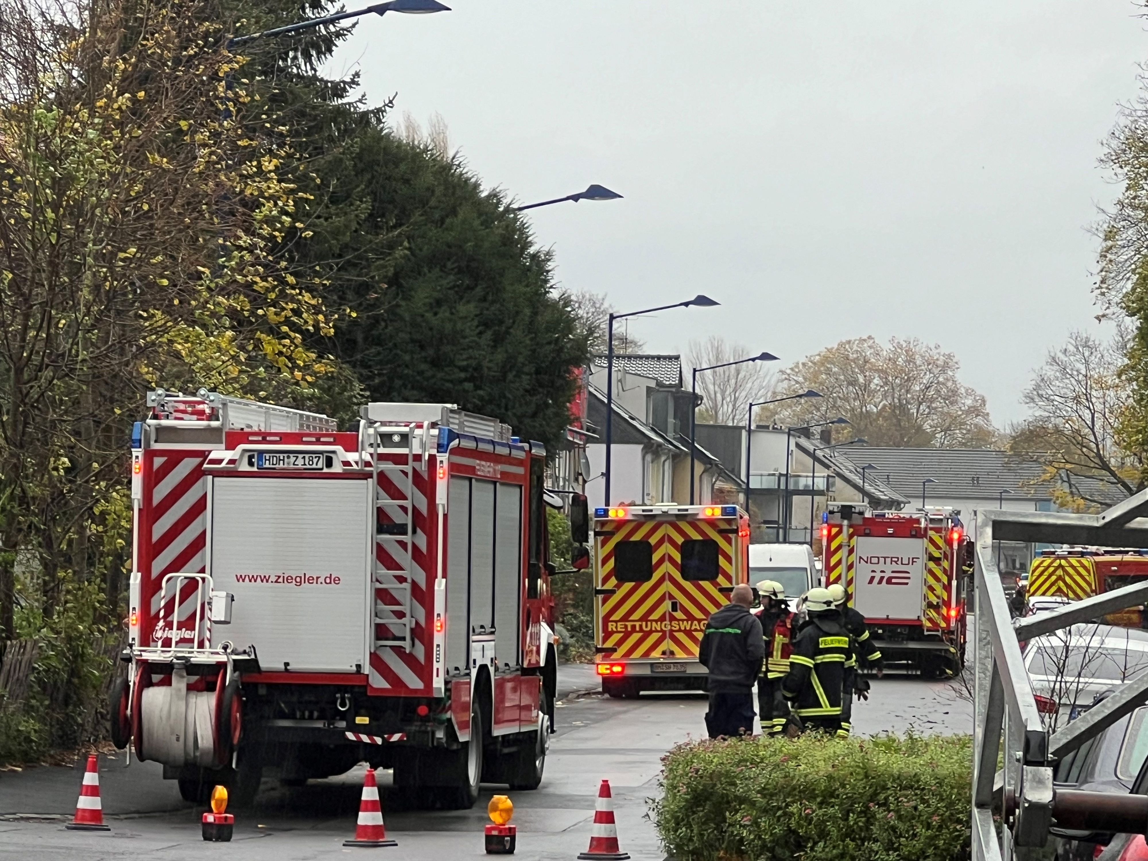 Das Bild zeigt mehrere Einsatzkräfte und mehrere Einsatzfahrzeuge der Feuerwehr auf einer Straße.
