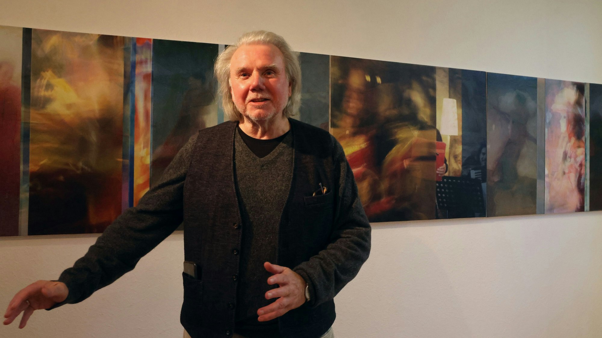 Künstler Lars Ulrich Schnackenberg steht in einer Ausstellung vor mehreren seiner eigenen Fotomontagen.