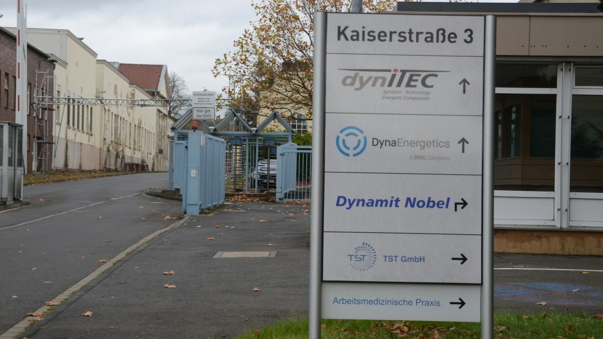 Die Einfahrt zu einem Industriepark. Auf einem Schild stehen mehrere Firmennamen.