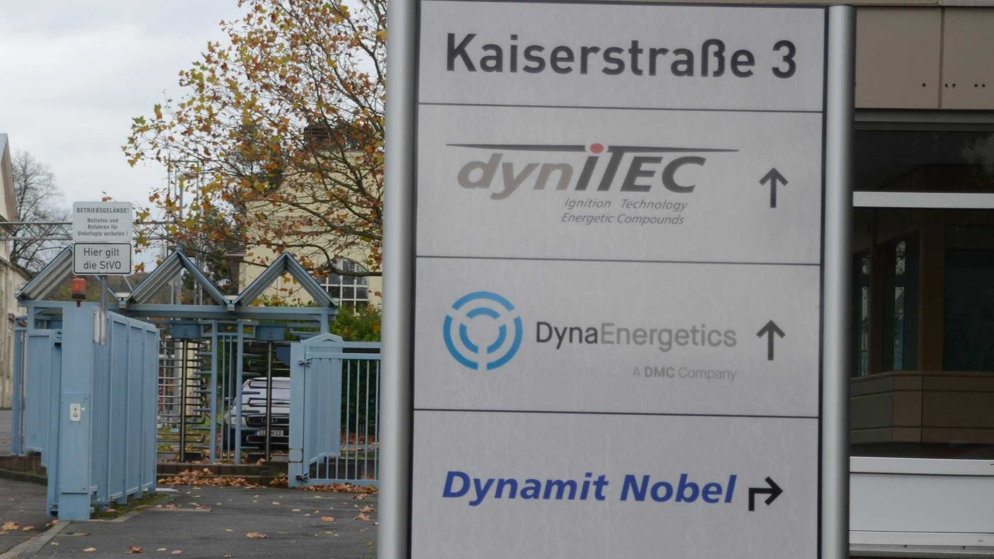 Eine Infotafel mit Firmennamen am Tor zu einem Industriegelände.