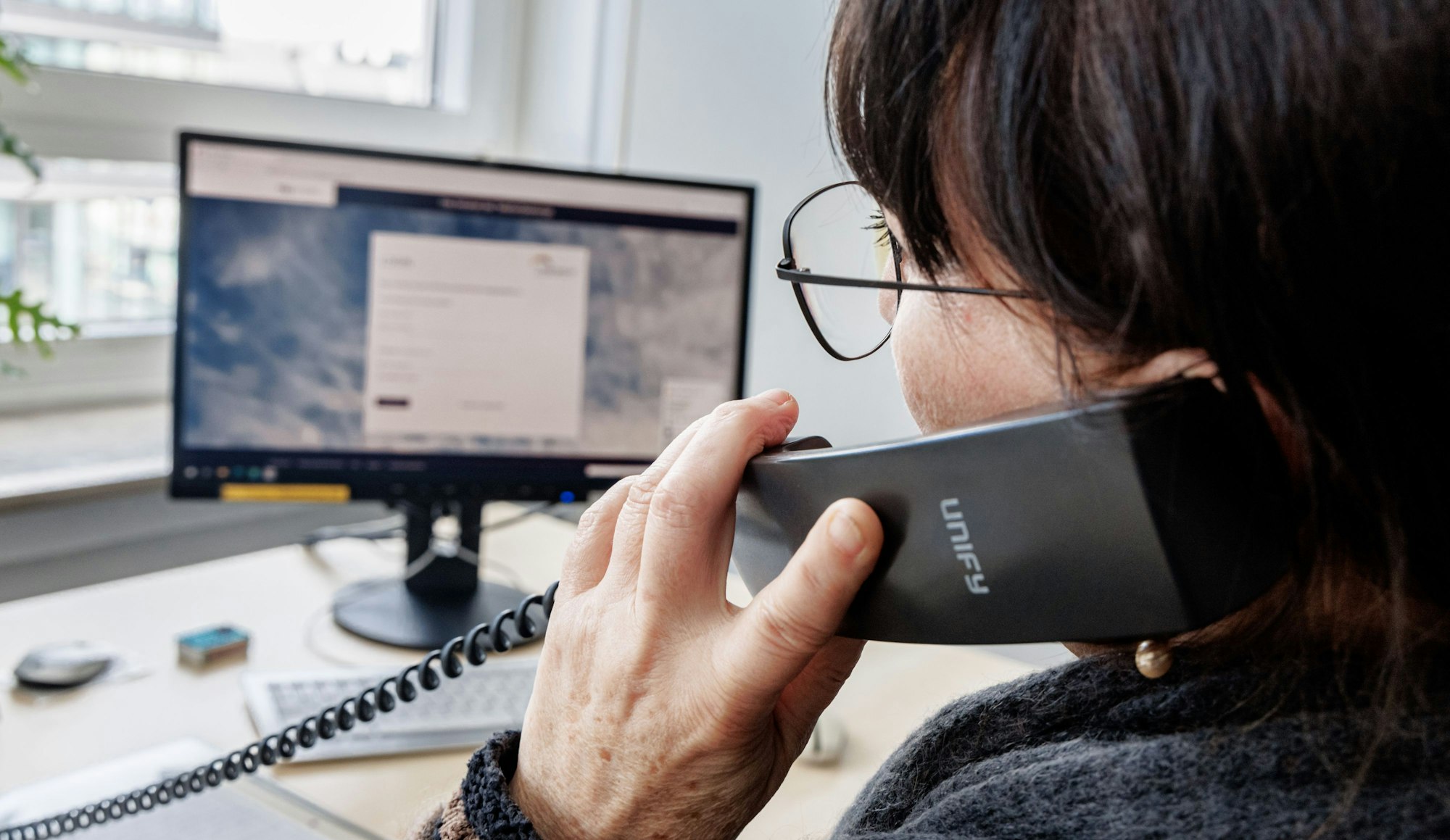 Eine Frau telefoniert am Schreibtisch.