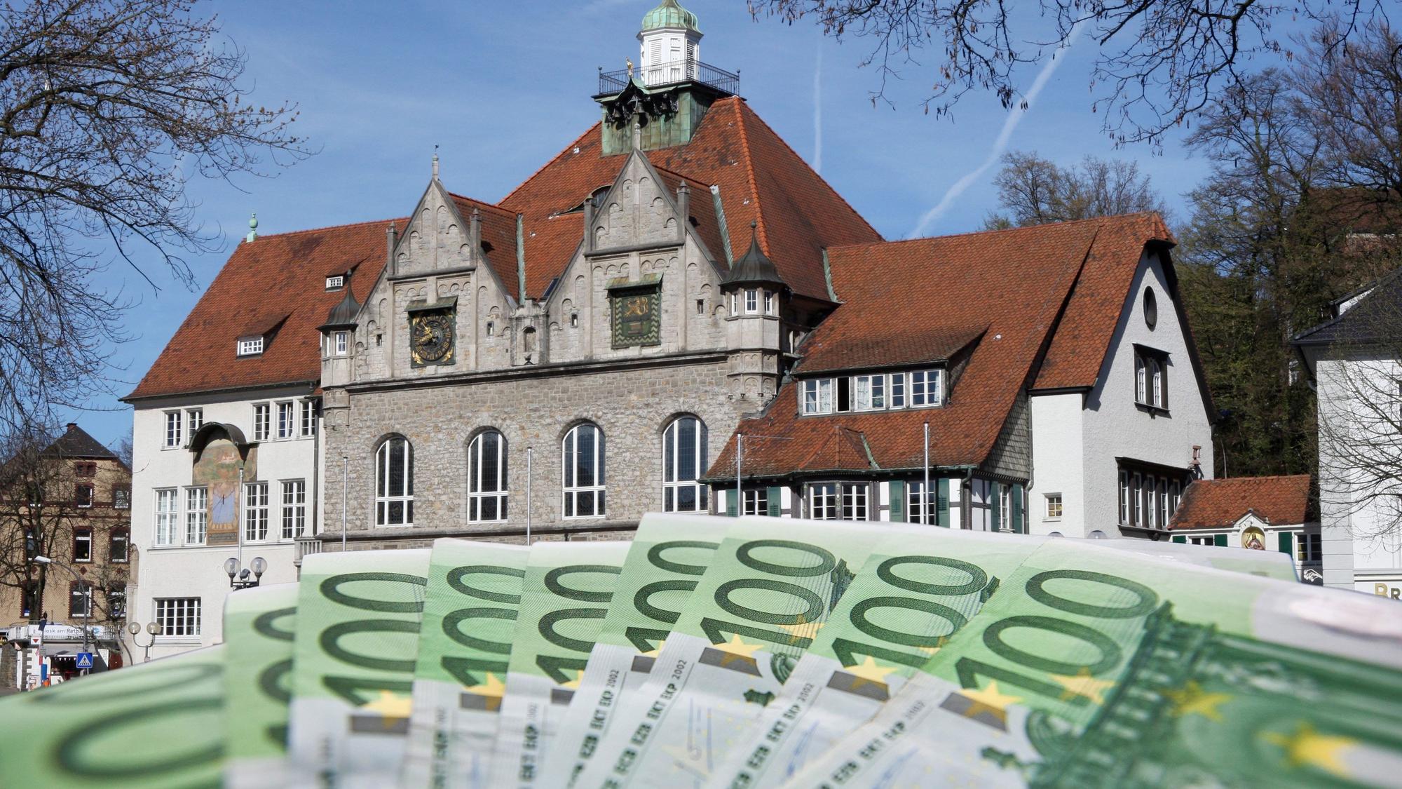 Das Foto zeigt das Gladbacher Rathaus und ein Bündel 100-Euro-Scheine