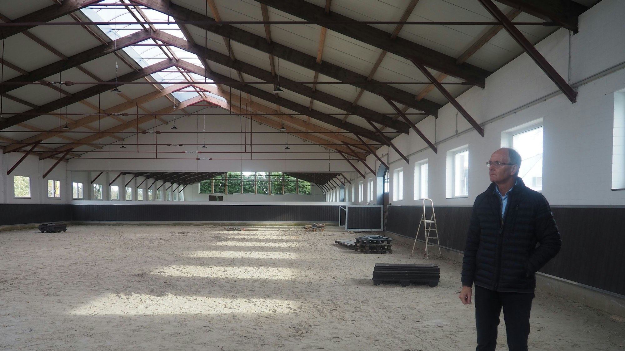 Ein Mann steht in einer Reithalle.