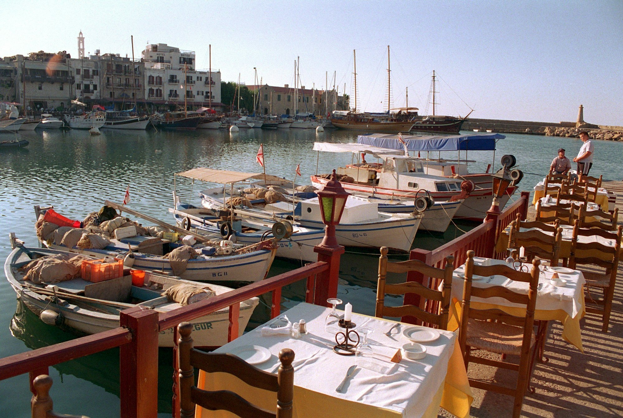 Gedeckte Tische auf der Terrasse eines Lokals, das direkt am malerischen Fischerhafen der Touristenhochburg Girne im türkischen Nord-Zypern liegt