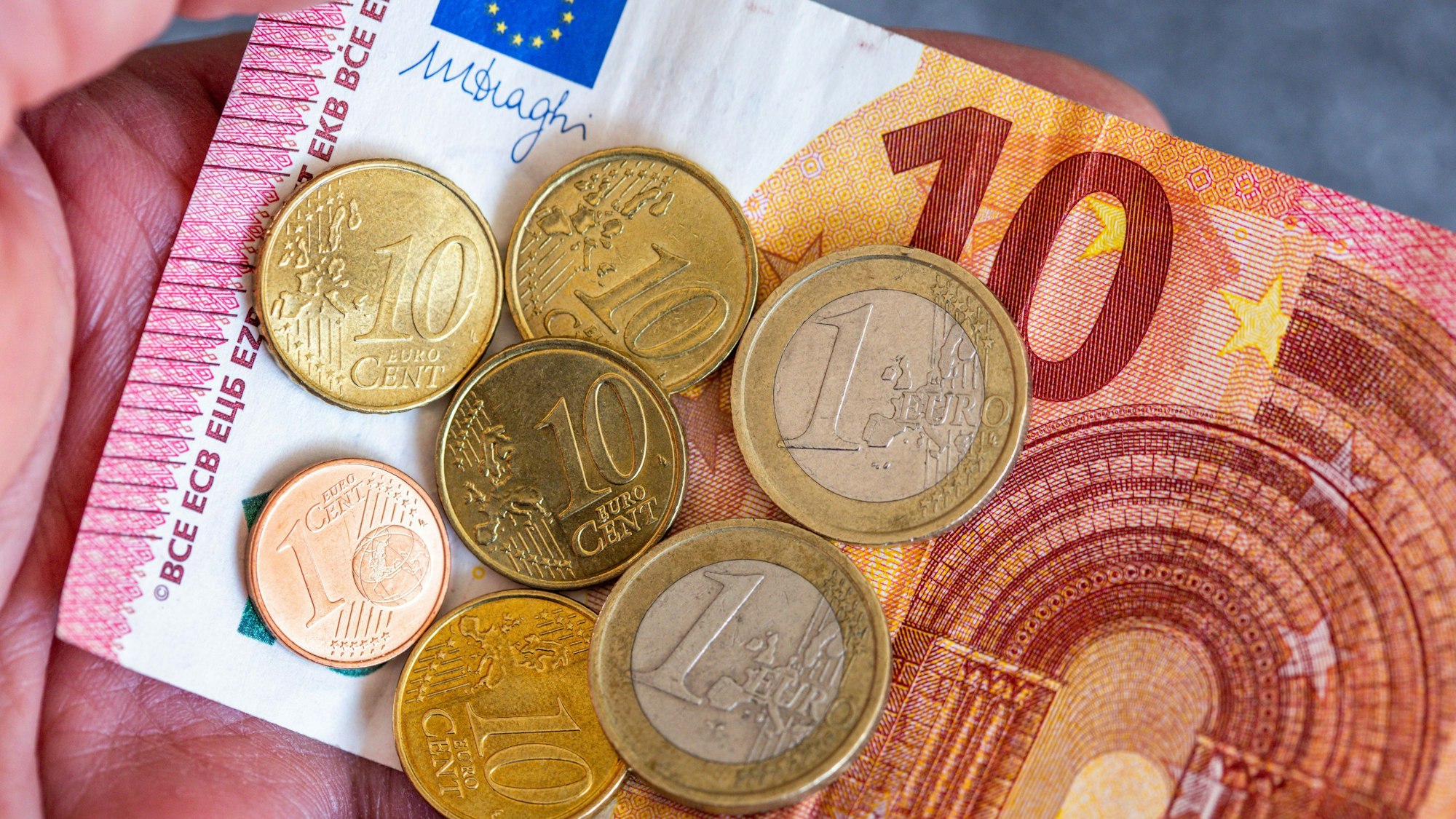ARCHIV - 26.06.2023, Berlin: Geldscheine und Euromünzen mit dem Wert von 12,41 Euro liegen auf einer Hand.