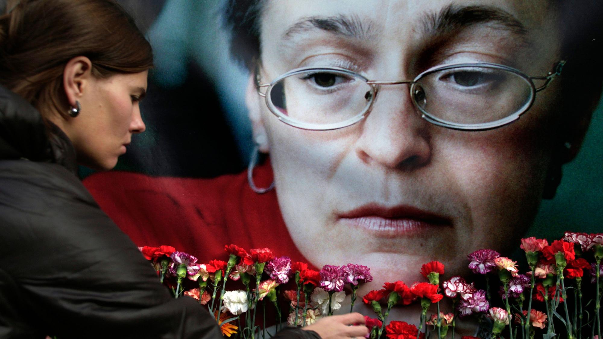 Eine Frau legt 2009 Blumen vor einem Porträt der ermordeten russischen Journalistin Anna Politkowskaja in Moskau nieder.