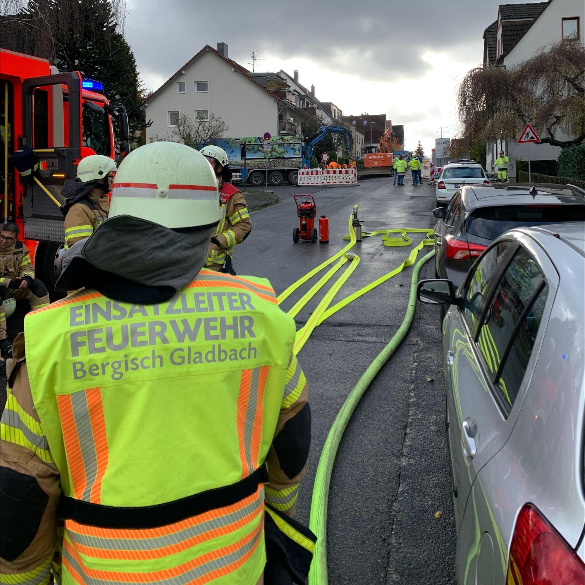 Ein Feuerwehrmann mit einer gelben Weste und der Aufschrift „Einsatzleiter“ steht an einer Einsatzstelle auf einer Straße.