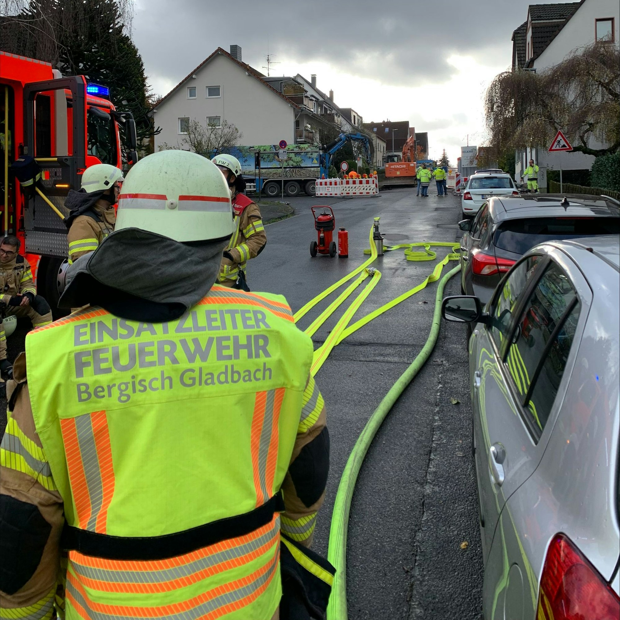 Ein Feuerwehrmann mit einer gelben Weste und der Aufschrift „Einsatzleiter“ steht an einer Einsatzstelle auf einer Straße.