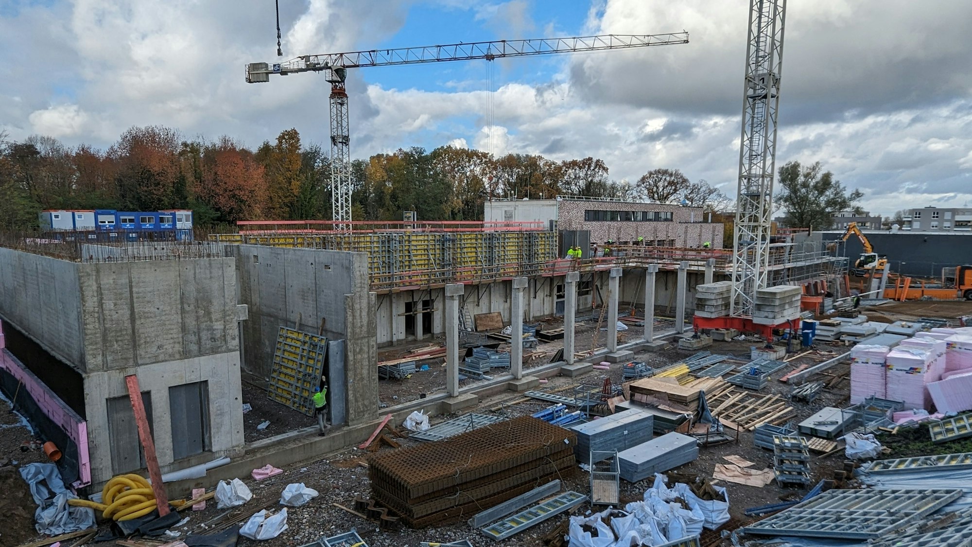 Ein Rohbau mit Baurkränen und viel Baumaterial.