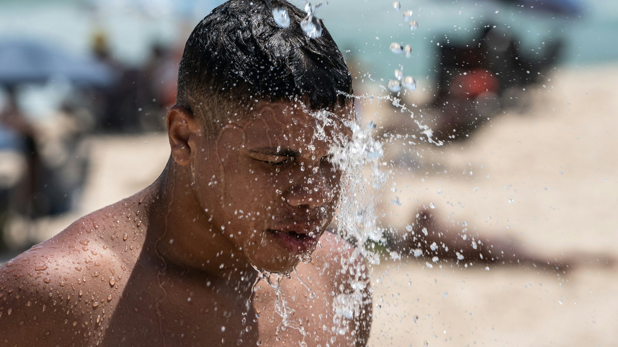 14.11.2023, Brasilien, Rio De Janeiro: Ein Mann duscht am Strand von Ipanema. Brasilien wird derzeit von einer Hitzewelle heimgesucht. Foto: Wang Tiancong/XinHua/dpa +++ dpa-Bildfunk +++