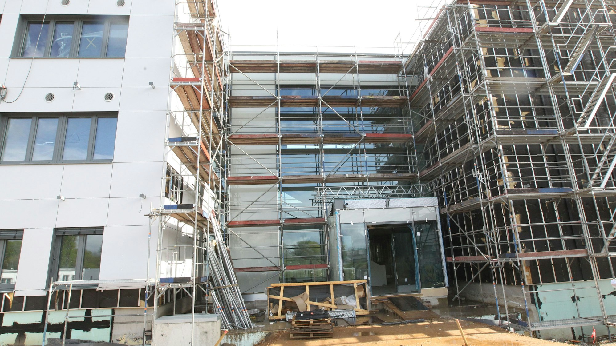 Die Baustelle eines großen Schulgebäudes. Ein Teil ist noch eingerüstet.