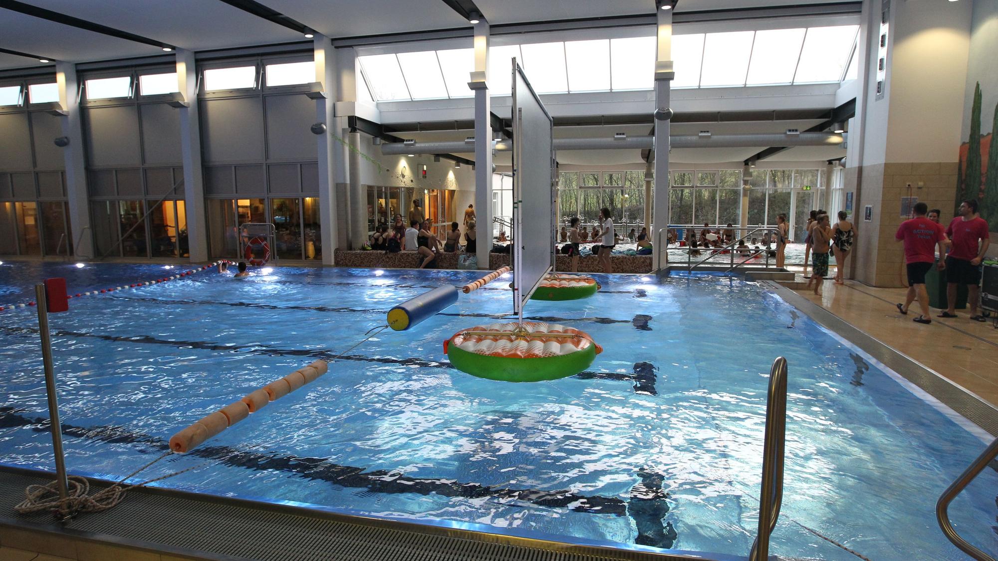 Das Aquarena-Hallenbad in Neunkirchen: Wasser glitzert im Becken, Menschen stehen am Beckenrand.