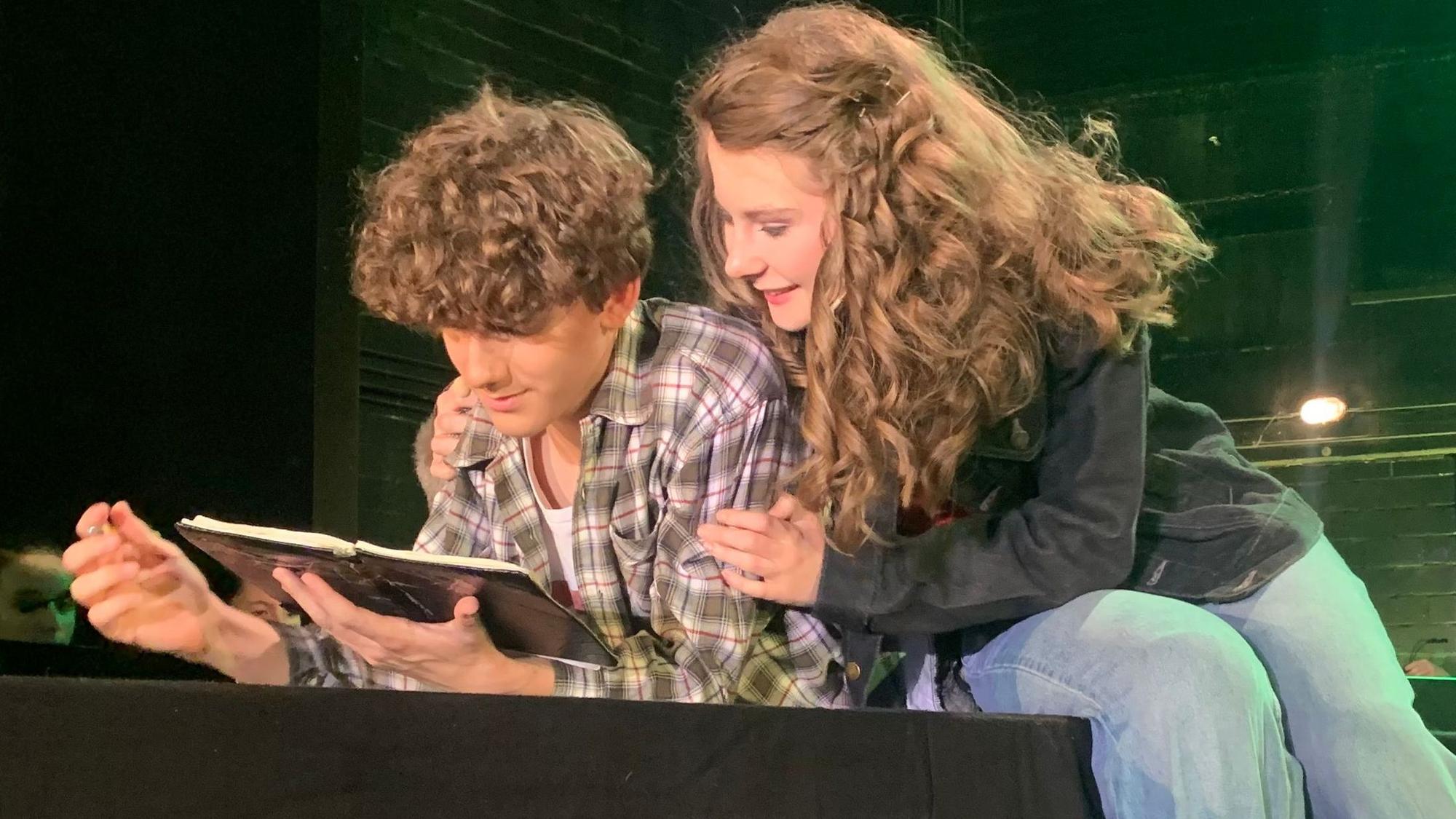 Die verliebten Hauptdarsteller Tom und Anne lesen zusammen in einem Buch beim Oberstufenmusical Chasing Shadow am Rhein-Sieg-Gymnasium.