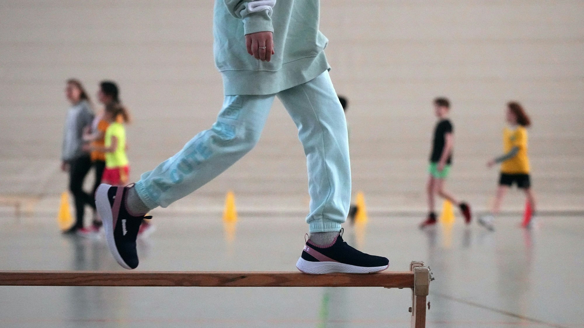 Eine Schülerin der 5. Klasse der Berliner Hunsrück-Grundschule läuft im Sportunterricht über eine umgedrehte Holzbank