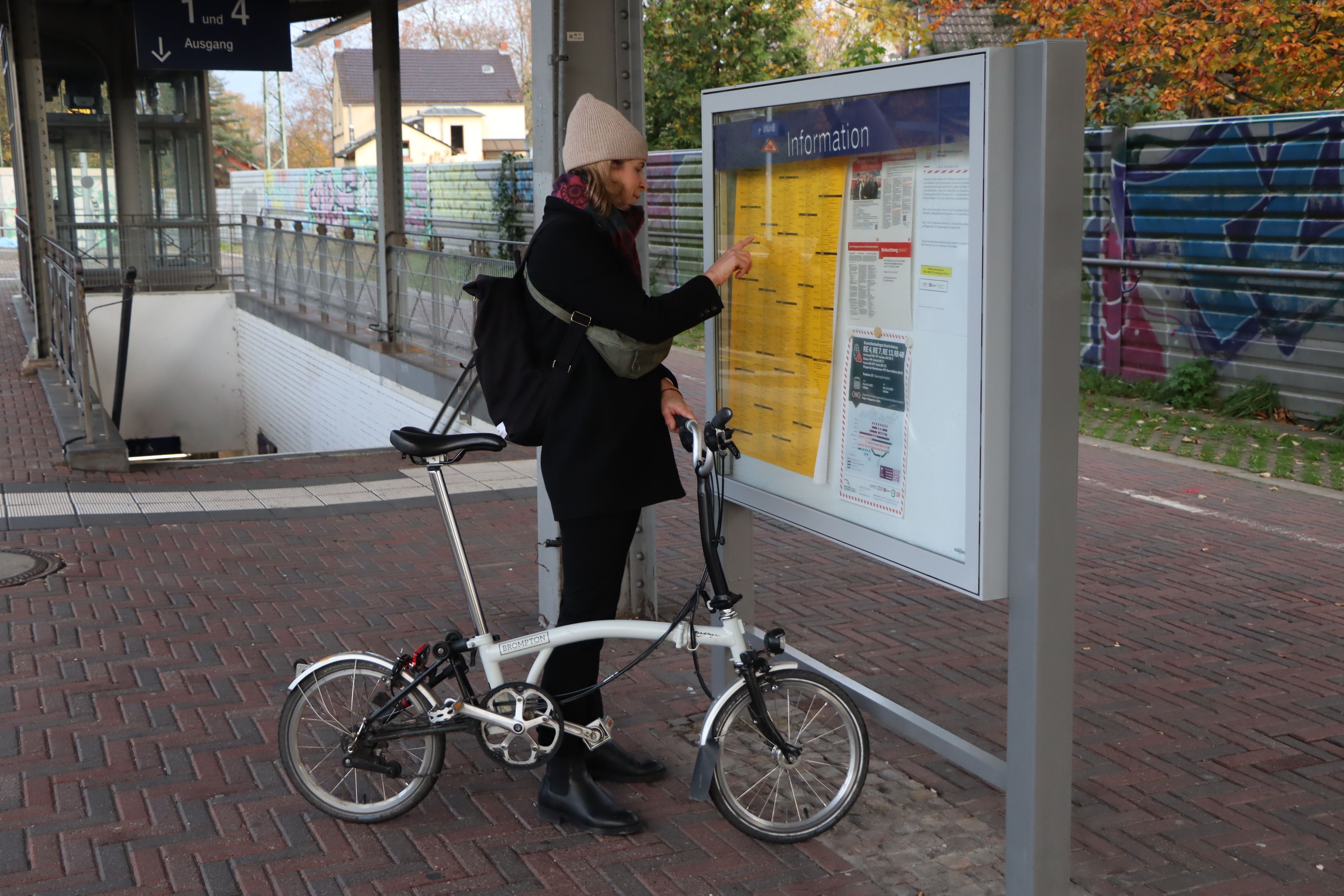 Das Bild zeigt eine Frau auf dem Bahnhof in Brühl vor dem Fahrplan.
