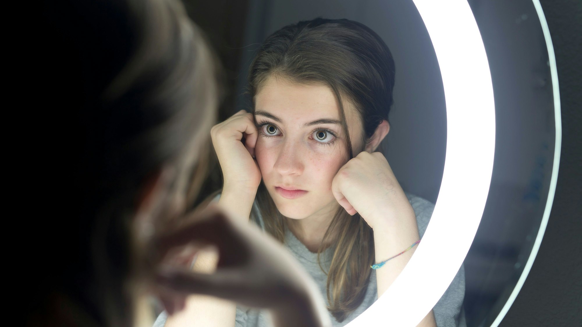 Junges Mädchen schaut sich im Spiegel an