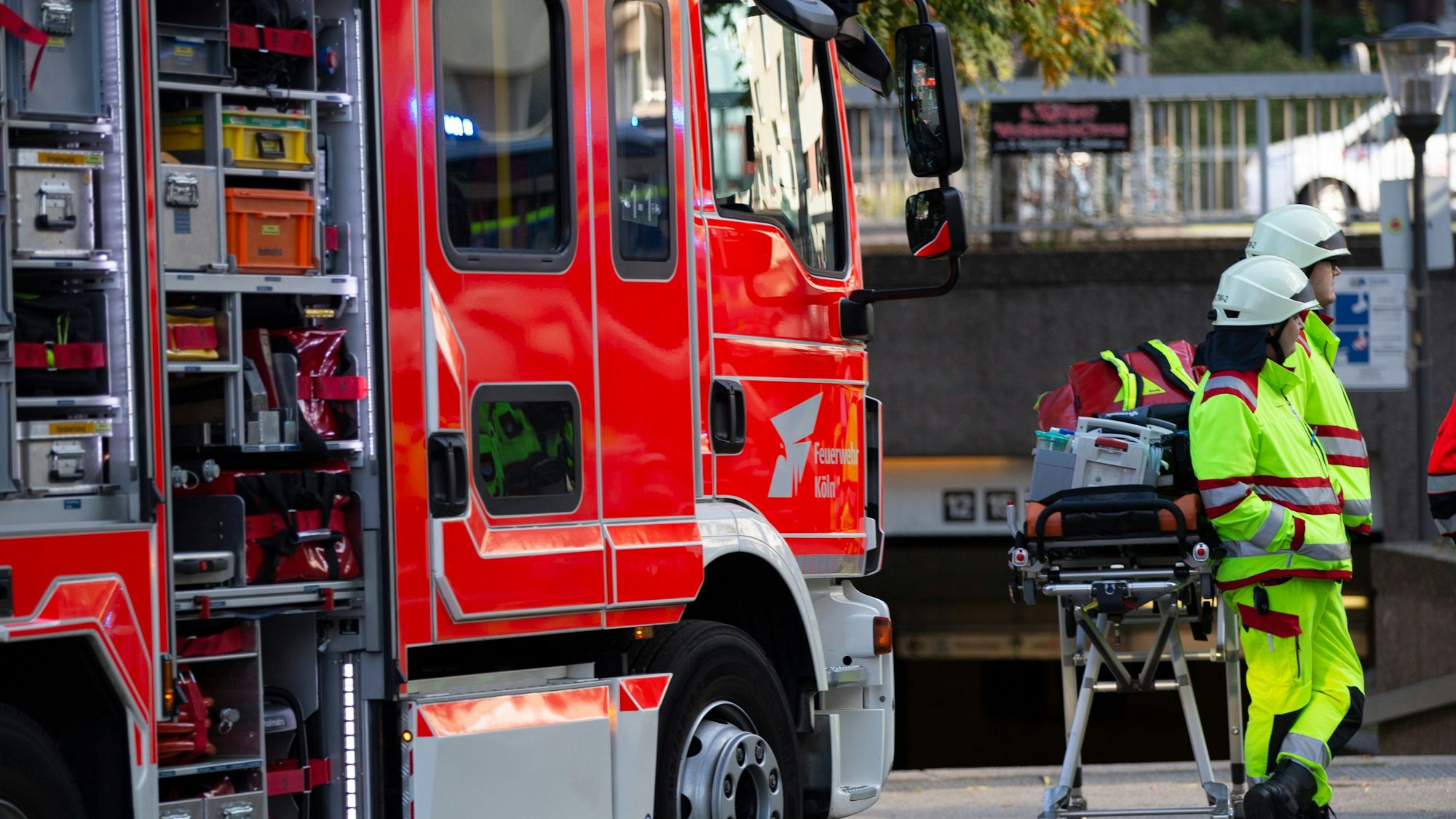 Zwei Mitarbeiter der Feuerwehr stehen neben einem Einsatzfahrzeug und einer Trage.