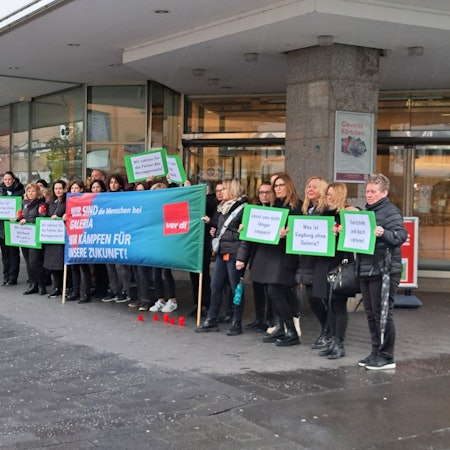Männer und Frauen mit einem Banner stehen vor dem Siegburger Kaufhof.