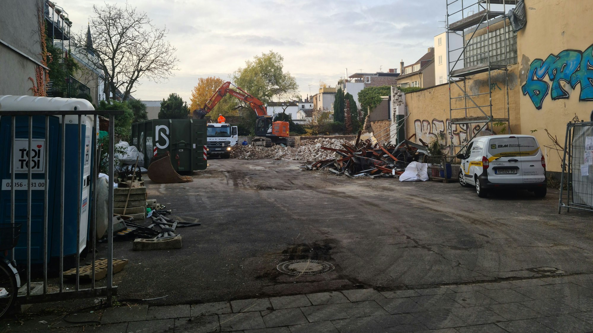 Blick auf ein großes Grundstück, auf dem Trümmer per Bagger auf einen Lastwagen geschaufelt werden.
