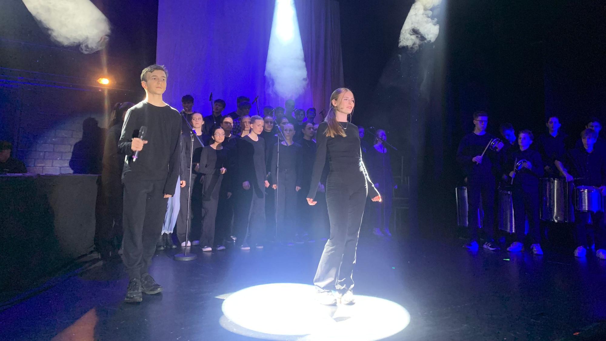Der Chor singt auf der Bühne beim Oberstufenmusical Chasing Shadow am Rhein-Sieg-Gymnasium in Sankt Augustin.