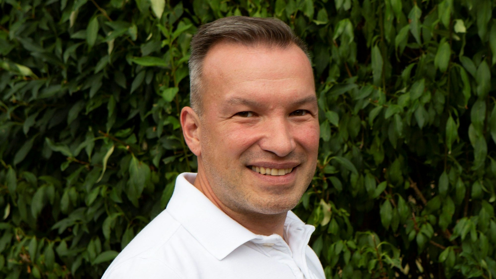 SPD-Fraktionschef Karl Michalowski steht vor einer Hecke.