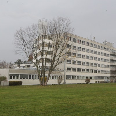 Eine Rasenfläche, im Hintergrund ein mehrgeschossiges Krankenhausgebäude.