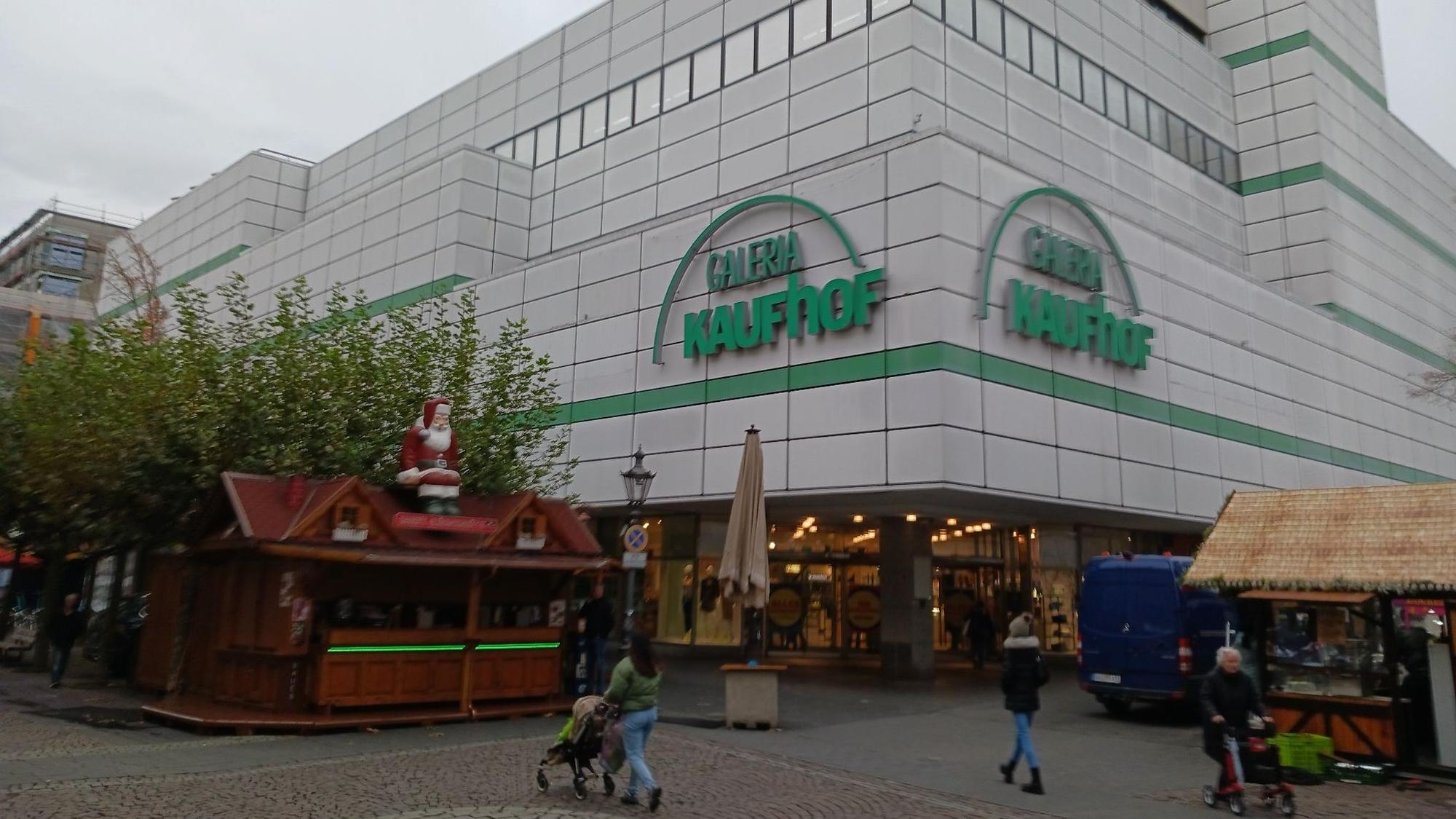 Ein Warenhaus in einer Fußgängerzone, im Vordergrund ein Glühweinstand