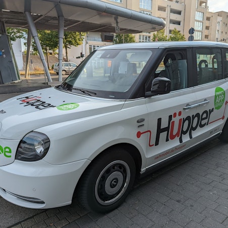 Ein Großraumtaxi mit der Aufschrift Hüpper am Busbahnhof in Hürth-Mitte.