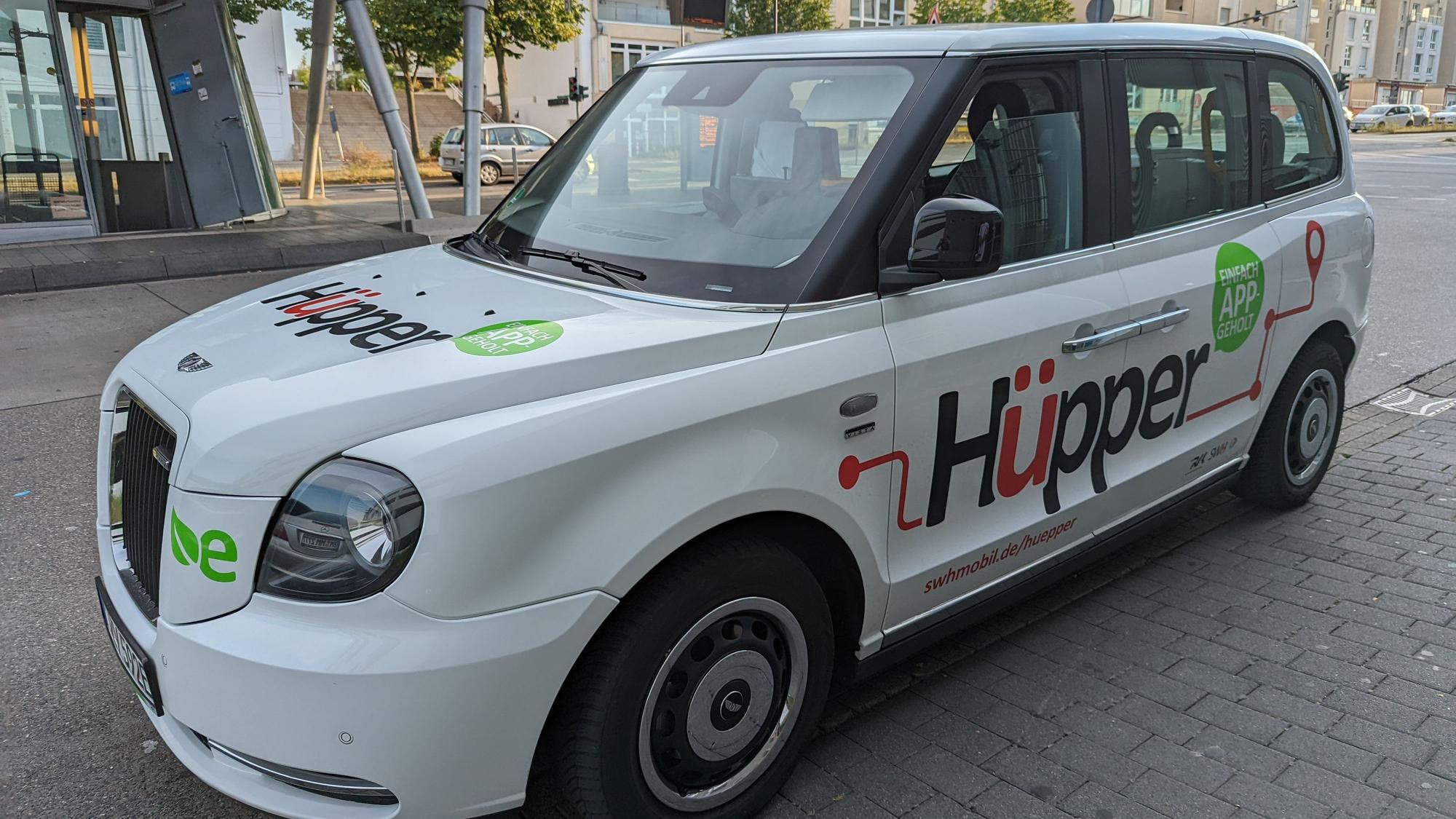 Ein Großraumtaxi mit der Aufschrift Hüpper am Busbahnhof in Hürth-Mitte.