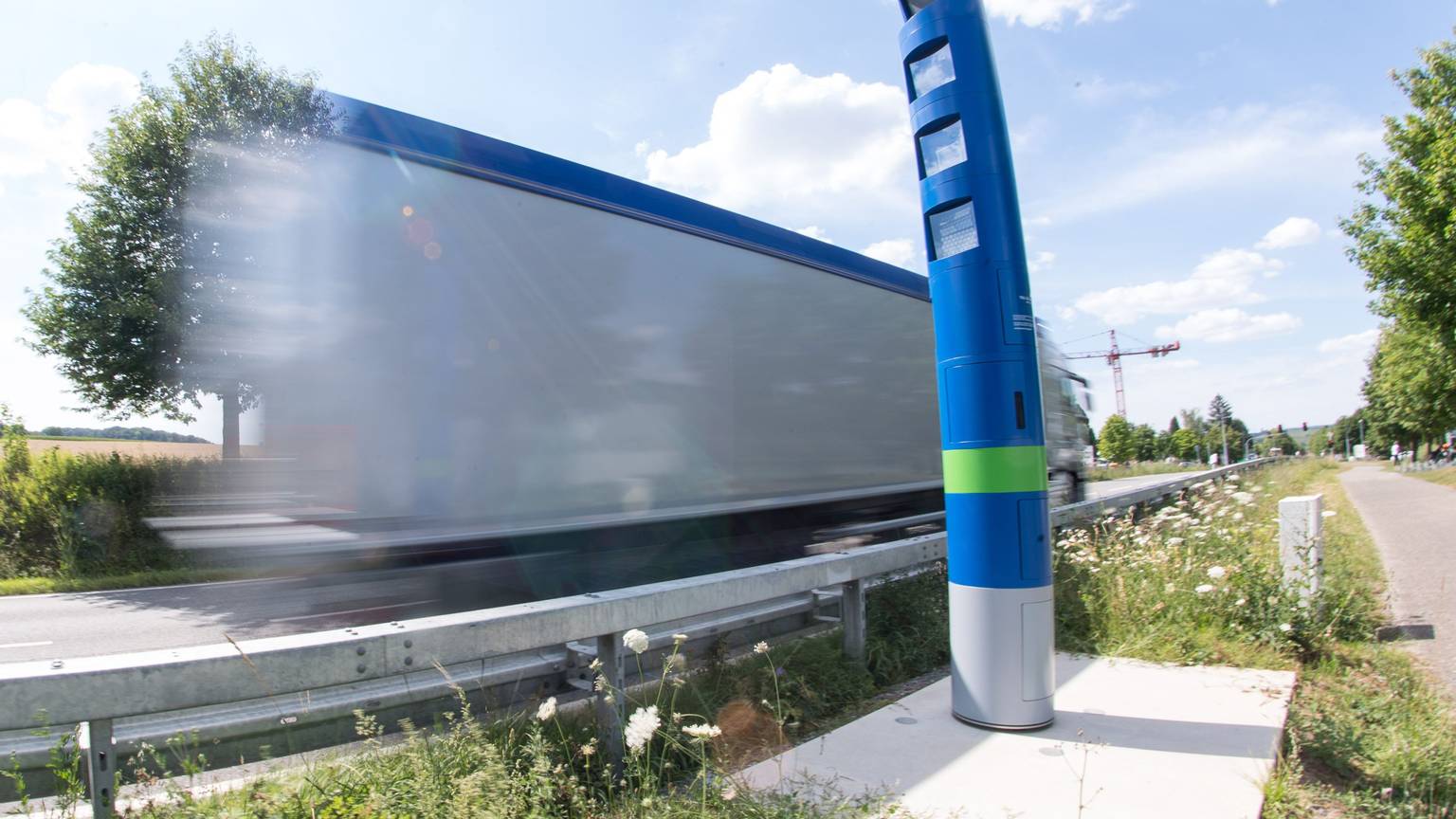 Ein Lastwagen fährt an einer Mautsäule auf einer Bundesstraße vorbei (Wischeffekt durch Langzeitbelichtung)
