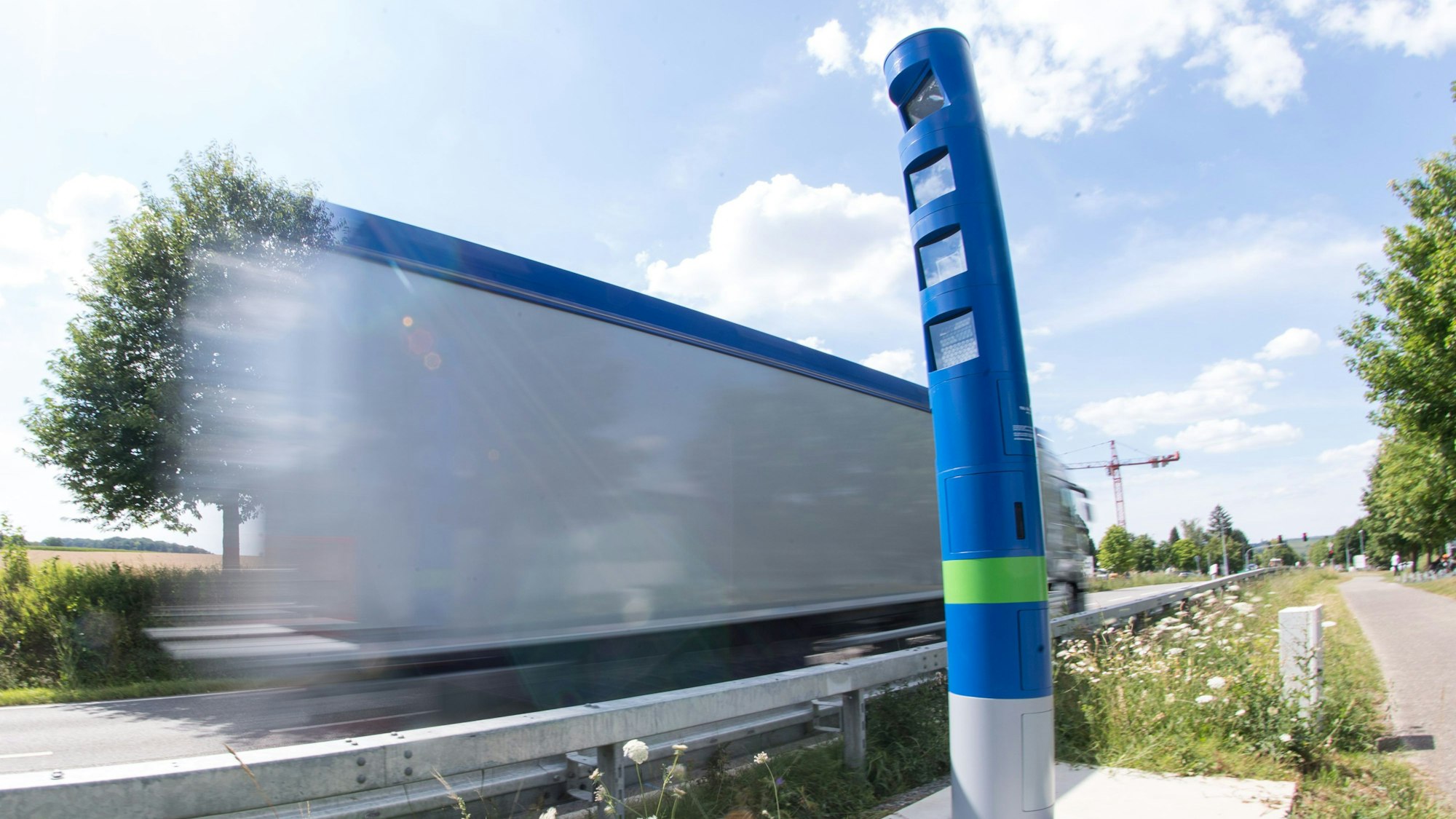Ein Lastwagen fährt an einer Mautsäule auf einer Bundesstraße vorbei (Wischeffekt durch Langzeitbelichtung)