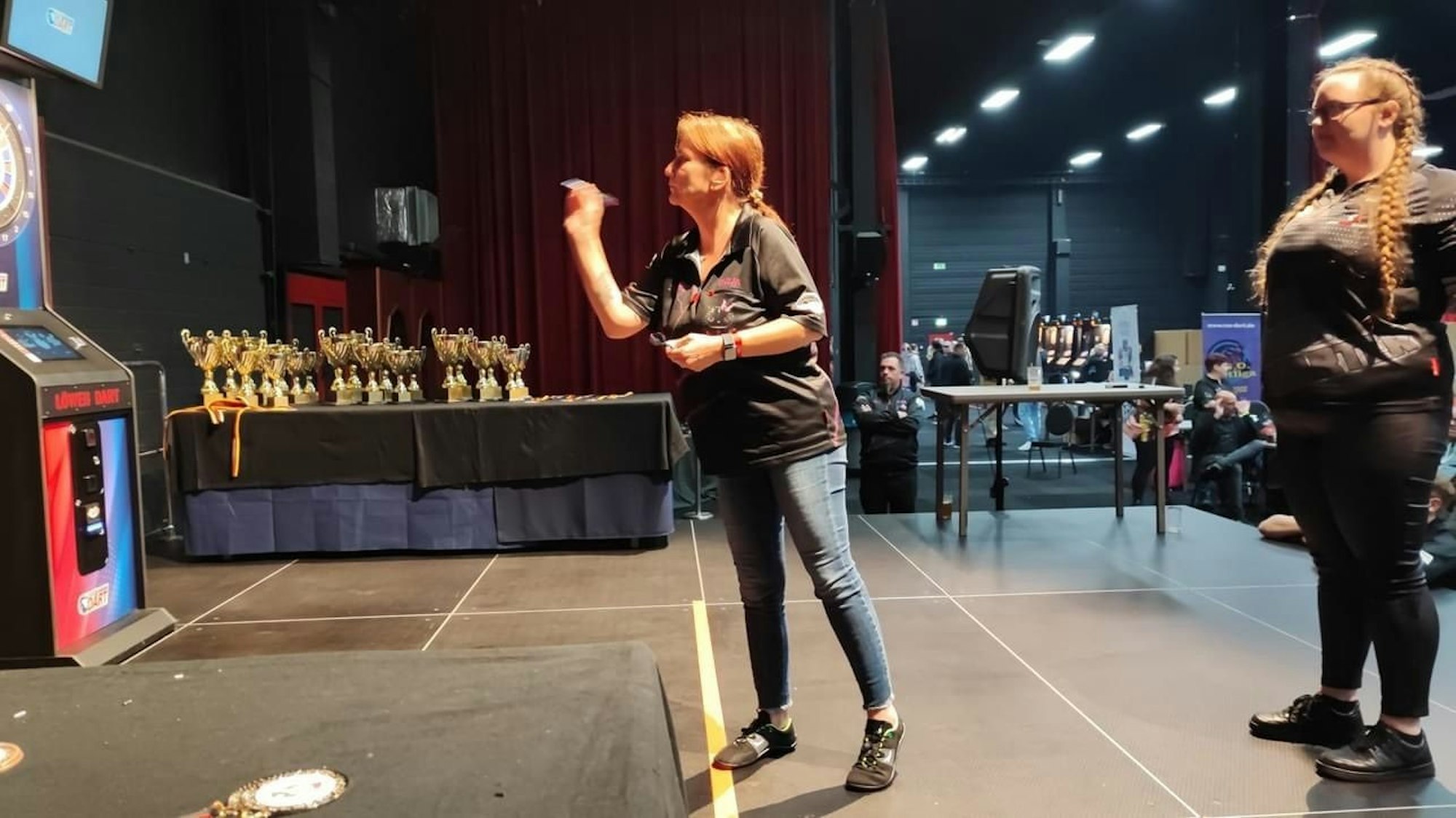 Eine Frau wirft einen Dartpfeil auf ein Board.