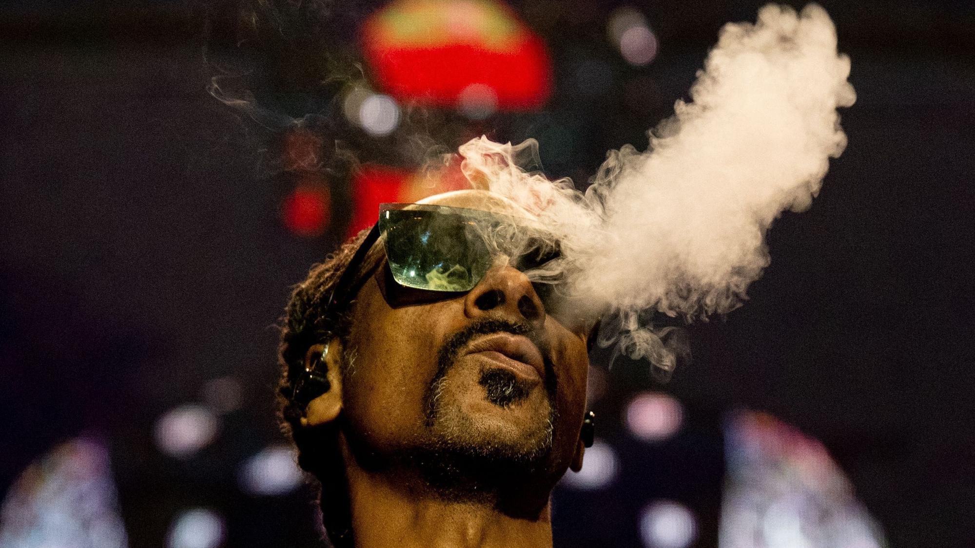 Der US-Rapper Calvin Broadus pustet Rauch aus, während er eine Sonnenbrille trägt.