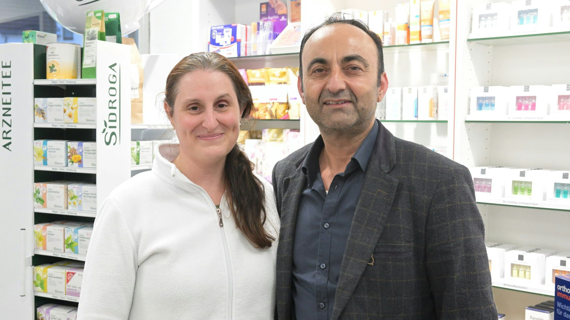 Isabel Hanisch-Alsultan und Azam Alsultan stehen nebeneinander vor einem Regal mit Medikamenten.