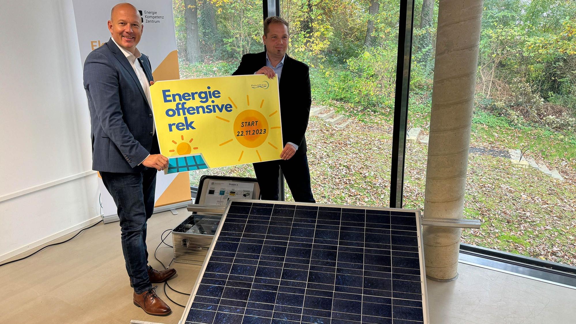Auf dem Foto sind Landrat Frank Rock und Umweltdezernent Uwe Zaar zu sehen. Sie halten ein Plakat hoch, auf dem eine Sonne zu sehen ist.