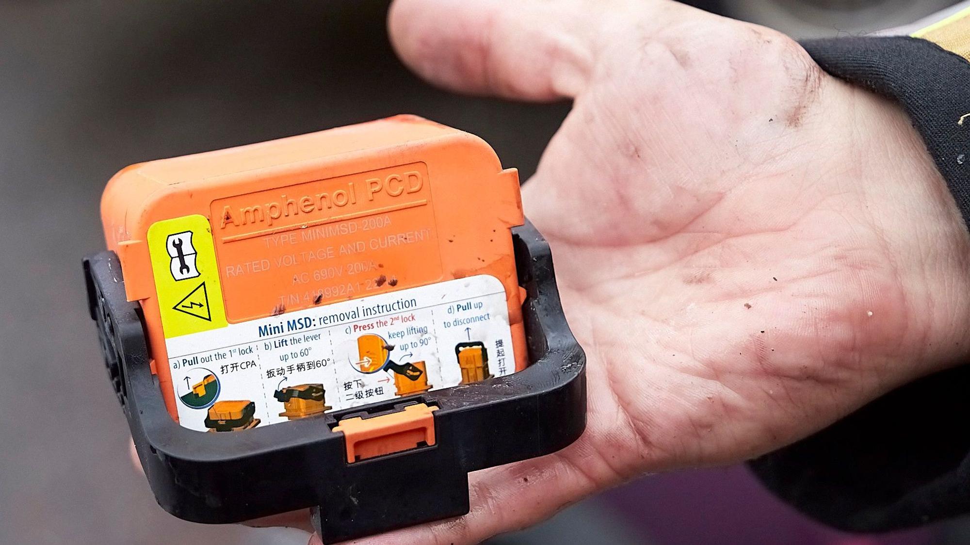 Ein Feuerwehrmann hat den orangefarbenen Schalter in der Hand.