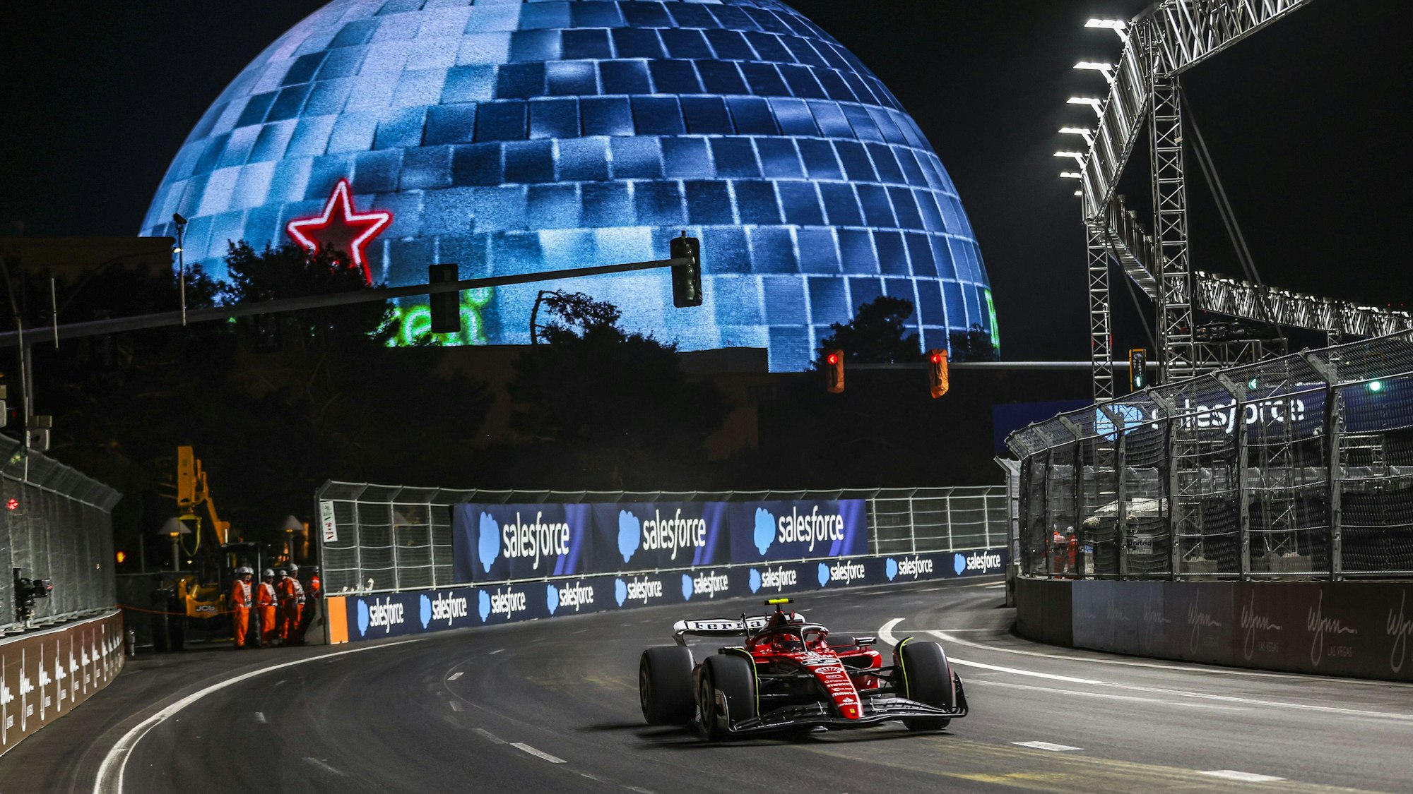 Carlos Sainz fährt mit seinem Ferrari über den Las Vegas Boulevard beim Formel-1-Rennen. Im Hintergrund ist die Las Vegas Sphere zu sehen.