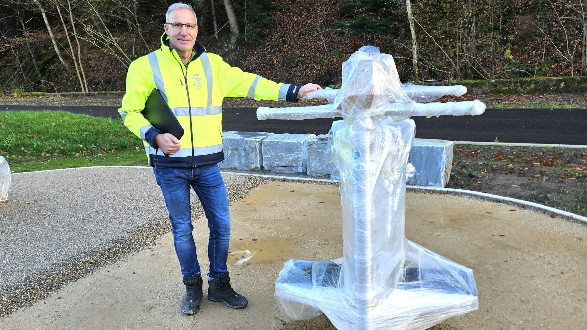 Jürgen Henz steht neben einem in Folie eingepackten Fitnessgerät.